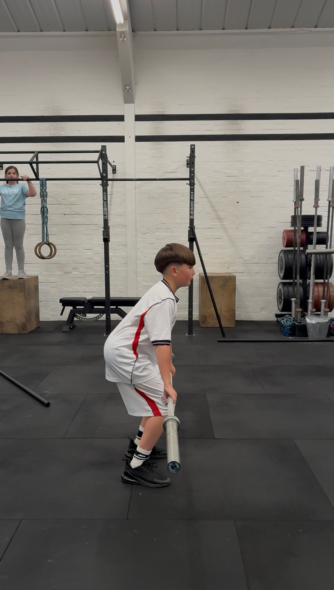 A child learning the deadlift position with a PVC pipe during CrossFit Kids coaching